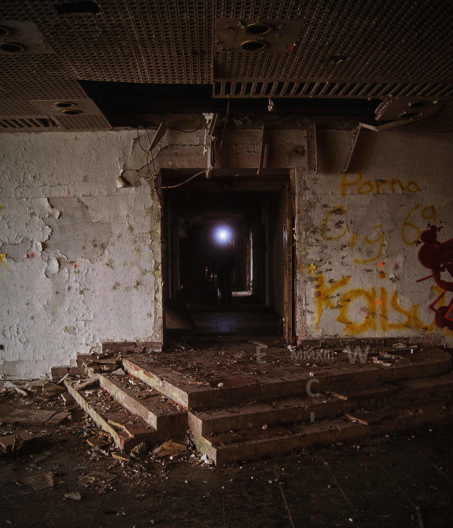 Eine Person mit Stirnlampe kommt aus einem dunklen Gang in einem Lost Place