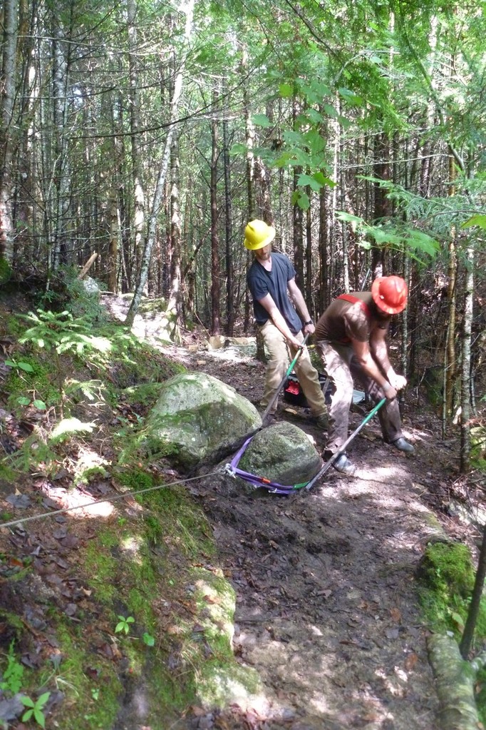 Ben and Robert work a stone out of the trail with rockbars as Chris applies a pulling force with the winch