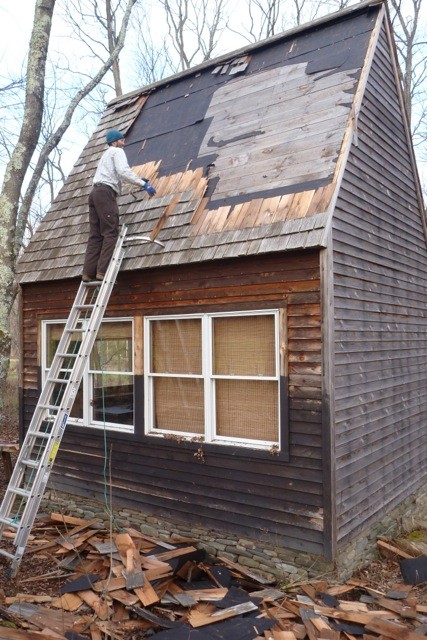 Work starts by stripping the red cedar shakes off the roof