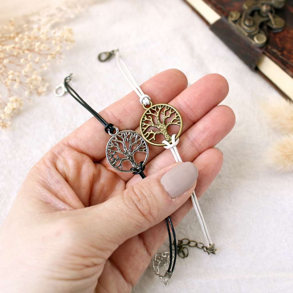 Zwei Lebensbaum-Armbänder in Schwarz und Weiß, in der Hand.