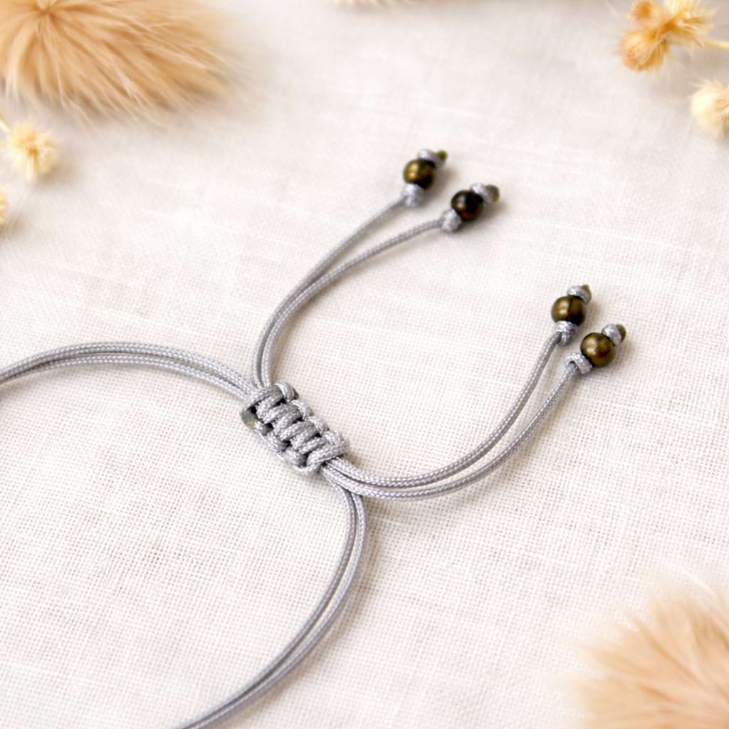 Graues Makramee‑Armband mit verstellbarem Knoten.