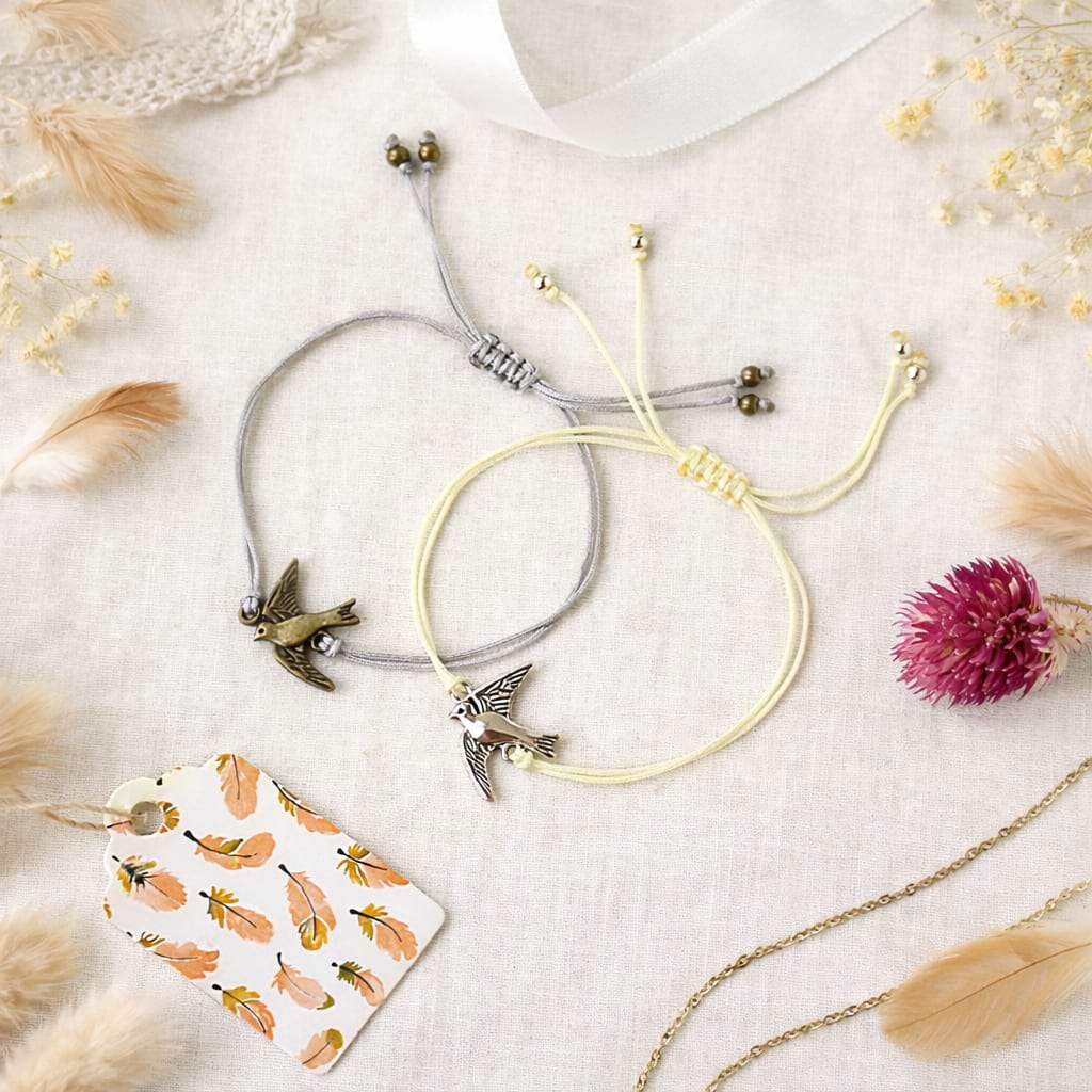 Zwei Makramee‑Armbänder mit Vogelanhängern.