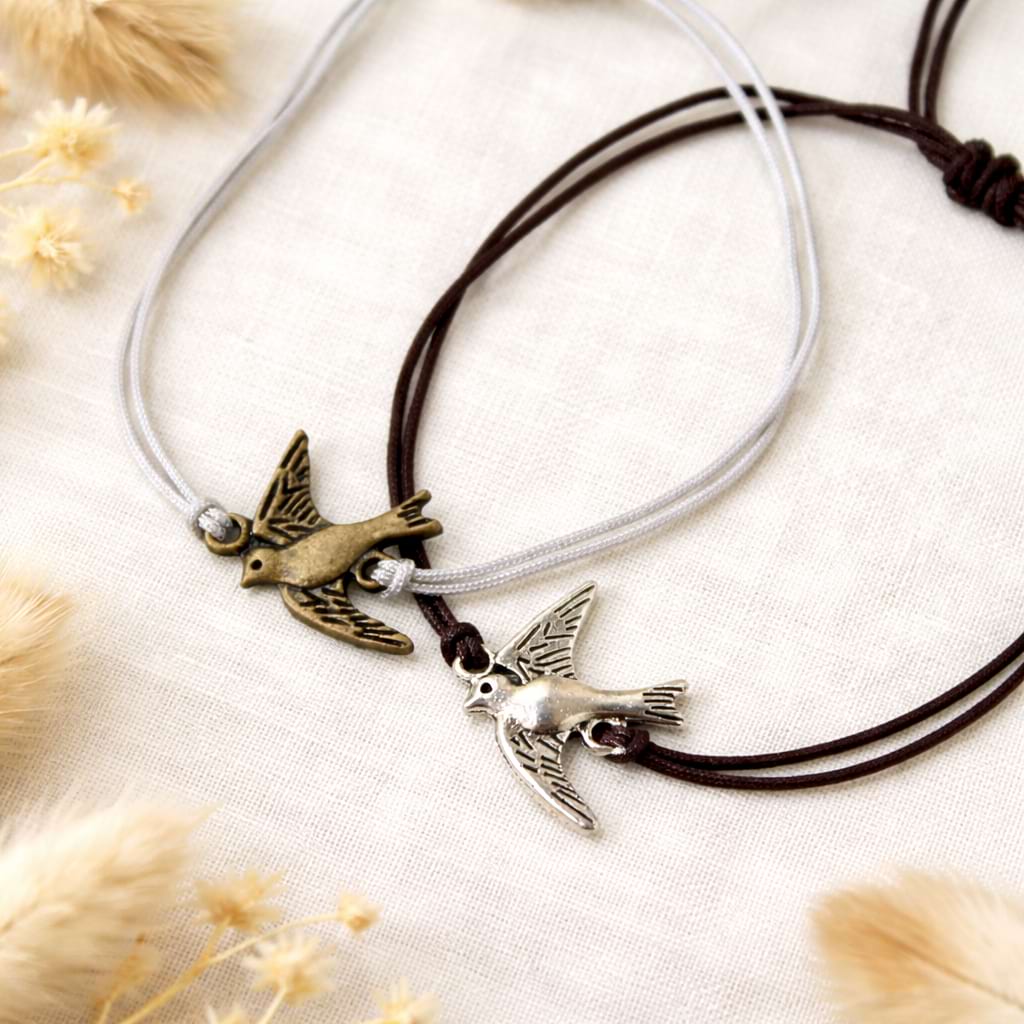 Zwei Makramee‑Armbänder mit Vogelanhängern.