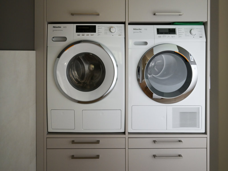 Platzoptimierter Hauswirtschaftsraum: Grauer Schrank für Waschmaschine und Trockner mit zusätzlichem Stauraum