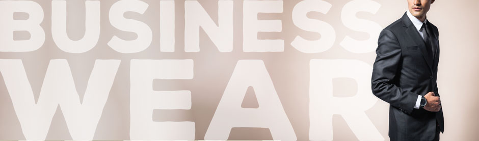Mann im eleganten Anzug mit Krawatte, im Hintergrund der Schriftzug „BUSINESS WEAR“.