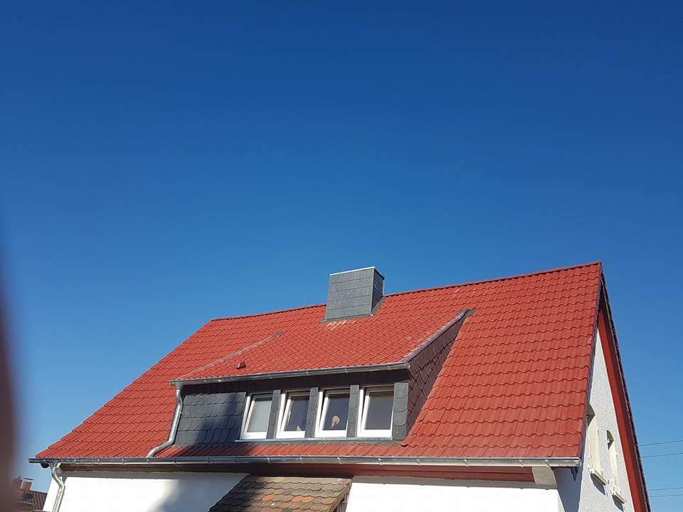 Eindeckung mit Betondachsteinen, Farbe Novo matt rot, Bekleidung der Gaube sowie Kamin mit Schieferschablonen