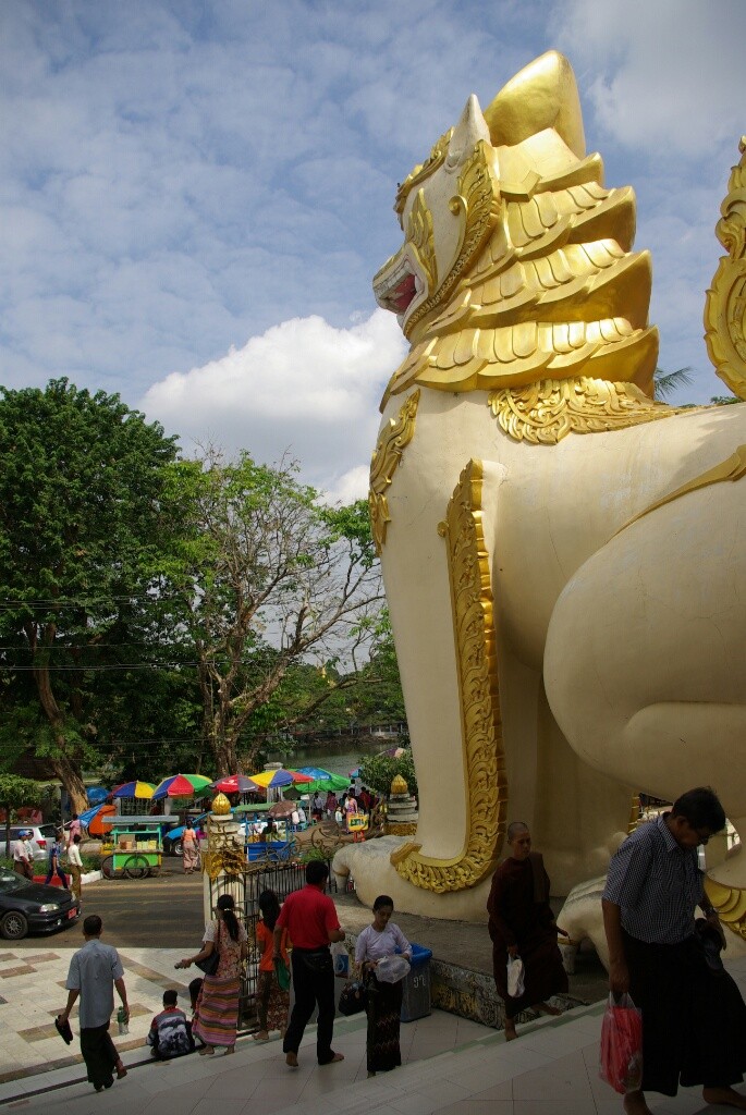 Zwei riesige Löwenfiguren bewachen den Eingang zur Shwedagon Pagoda.