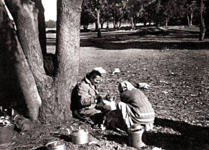 Meher Baba resting at one of the camp sites on a journey through India. Mehera Irani has prepared a meal for him.