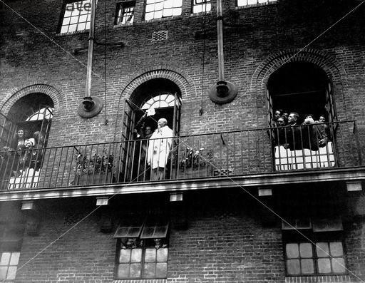 Gandhi standing at a verandar at Kingsley Hall 