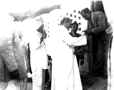 Meher Baba accepting "bhiksha" from Keki Nalavala during the New Life