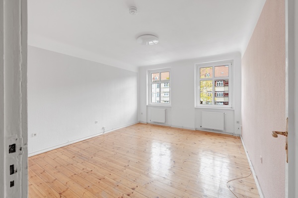 Wohnzimmer der Altbauwohnung in Berlin-Spandau mit zwei Fenstern und Dielenboden