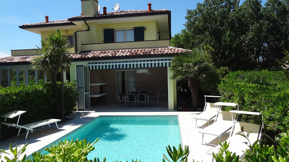 Ein Ferienhaus mit einem einladenden Pool und einer schönen Terrasse.