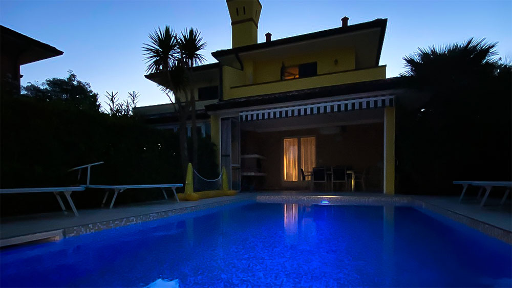 Ein Pool vor einem Ferienhaus in der Nacht, mit sanfter Beleuchtung, die eine entspannte Stimmung schafft.