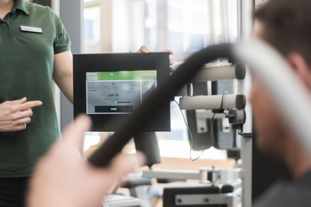 Eine Trainerin zeigt einem Kunden das Gerätetraining