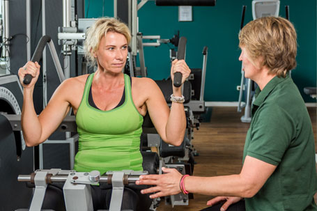 Eine Kundin wird beim Krafttraining von einer Personal Trainerin angeleitet