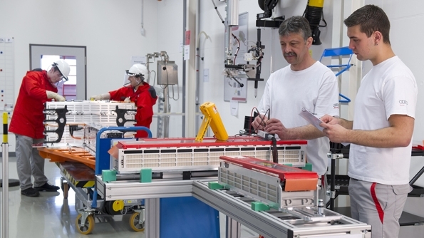 Vordergrund: Prüfung Spannungsabgriffe von Batteriezellen. Hintergrund: Elektrische Endmontage einer R8 e-tron Batterie.