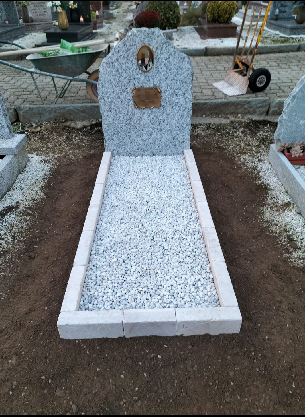 Copritomba modello roccioso in pietra di Serizzo e bordure a mattoncino in Trani