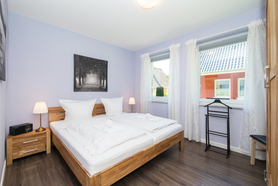 Schlafzimmer im Ferienhaus Thomsen-Detlefs auf Fehmarn mit einem bequemen Doppelbett, liebevoller Dekoration und einer hellen, freundlichen Atmosphäre für erholsame Nächte.