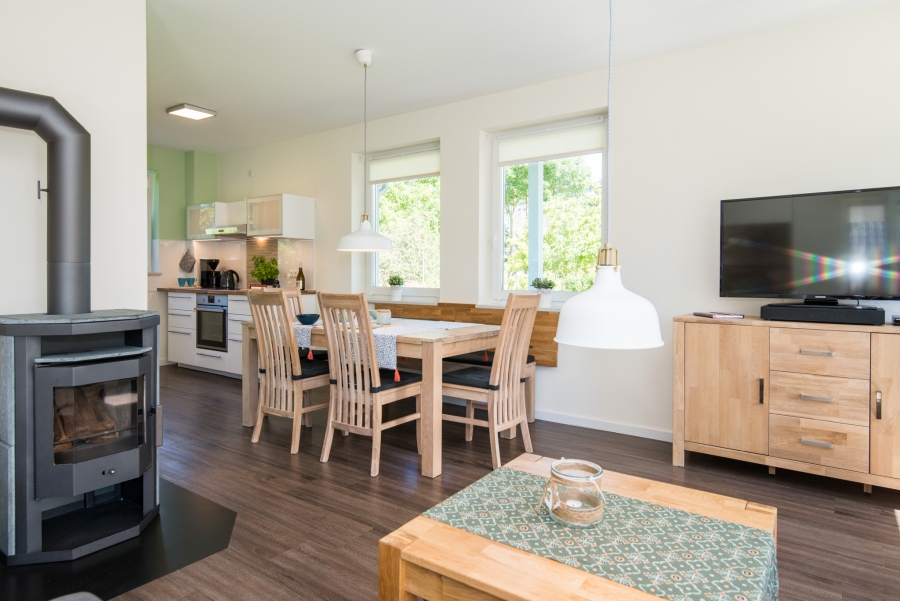 Offener Wohn-Essbereich im Ferienhaus auf Fehmarn mit einem großzügigen Esstisch für die ganze Familie direkt neben der modern ausgestatteten Küchenzeile.