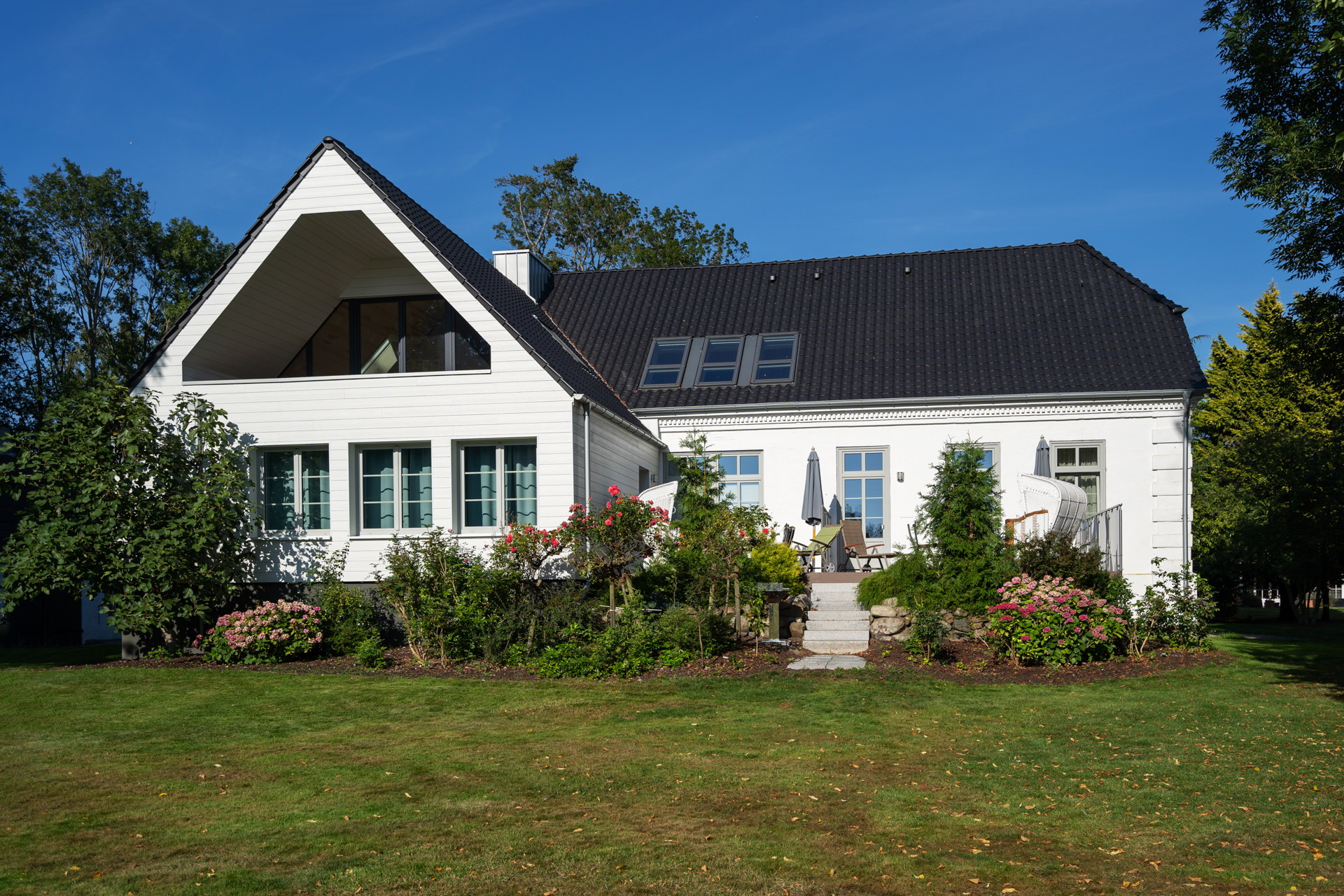 Gartenansicht des Herrenhauses (Baujahr 1850): Traditionelle Architektur und großzügiger Außenbereich für erholsame Urlaubstage auf der Insel Fehmarn.