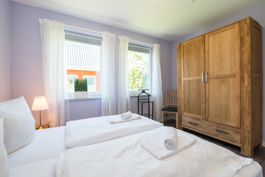 Schlafzimmer im Ferienhaus Thomsen-Detlefs auf Fehmarn mit einem bequemen Doppelbett, liebevoller Dekoration und einer hellen, freundlichen Atmosphäre für erholsame Nächte.