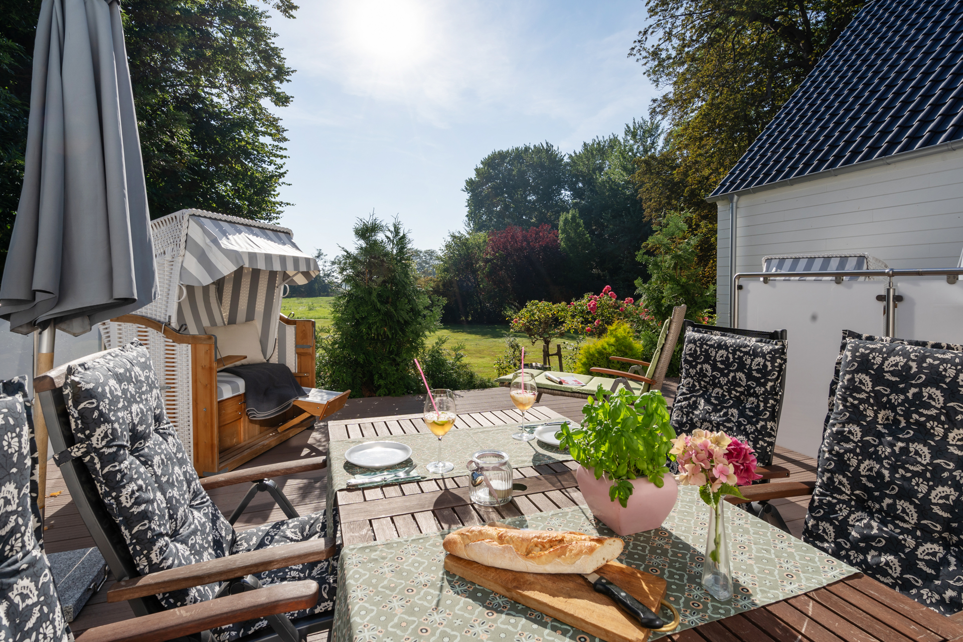 Exklusiver Außenbereich des Herrenzimmers: Großzügige Terrasse mit gemütlichem Strandkorb im Garten des historischen Herrenhauses von 1850.