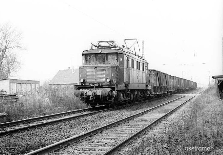 DR 244 108 kommt am 22.03.1985 mit einer schönen Leine offener Wagen aus Richtung Dessau durch Jeßnitz (Anhalt). Die Lok steht seit einigen Jahren im Bw Halle P. 