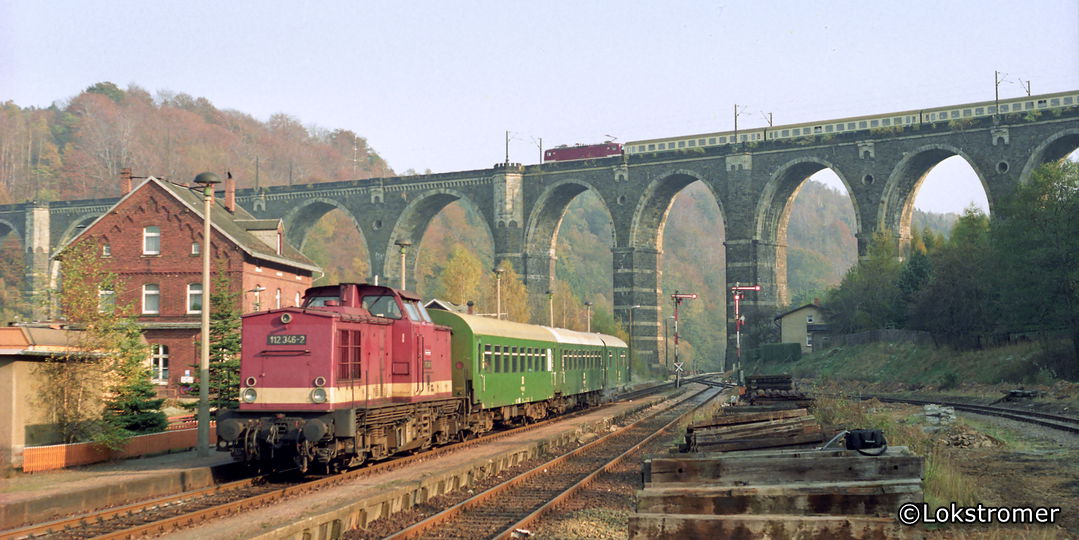 DR 112 346 am 31. Oktober 1991 mit einem Personenzug im Bahnhof Hetzdorf. Auf dem Hetzdorfer Viadukt fährt ein Schnellzug in Richtung Dresden.