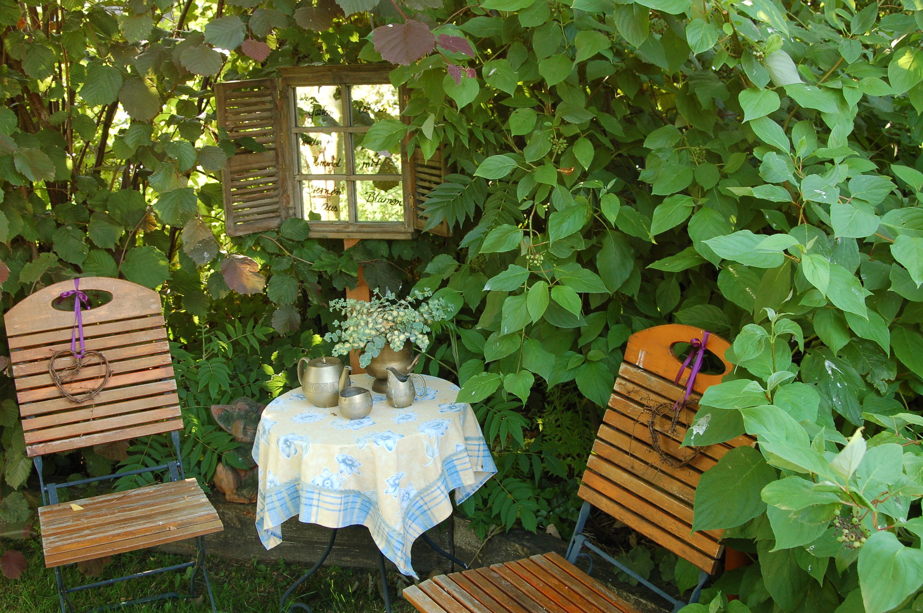 Sitzgelegenheiten in ihrem Garten sind prädestiniert für gestalterische Umtriebe. Hier sorgt ein Spiegel in einem Fensterrahmen für einen vorgetäuschten Blick in die Natur. Und das alte Kaffee- Geschirr findet auch einen neuen Platz. 