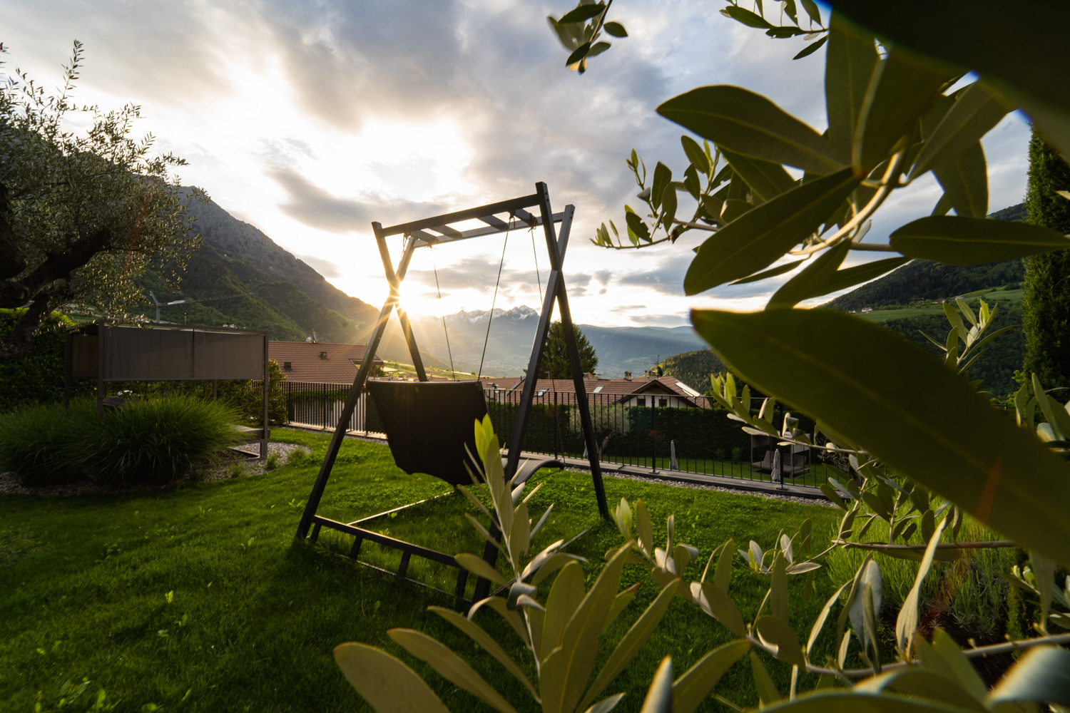 A hanging chair in the well-tended garden of the Hotel Mair in Living, Partschins near Merano in South Tyrol, offering panoramic views of the surrounding mountain landscape – a peaceful spot to relax and enjoy nature.