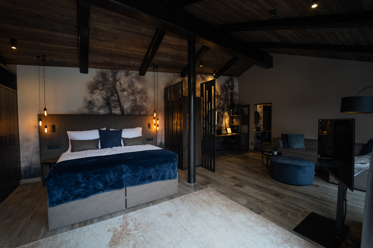 A spacious, modern suite at the Hotel Mair am Ort Living in Partschins near Merano in South Tyrol, featuring a comfortable double bed, a cosy living area, stylish design elements and a warm lighting scheme to create a relaxed, feel-good atmosphere.