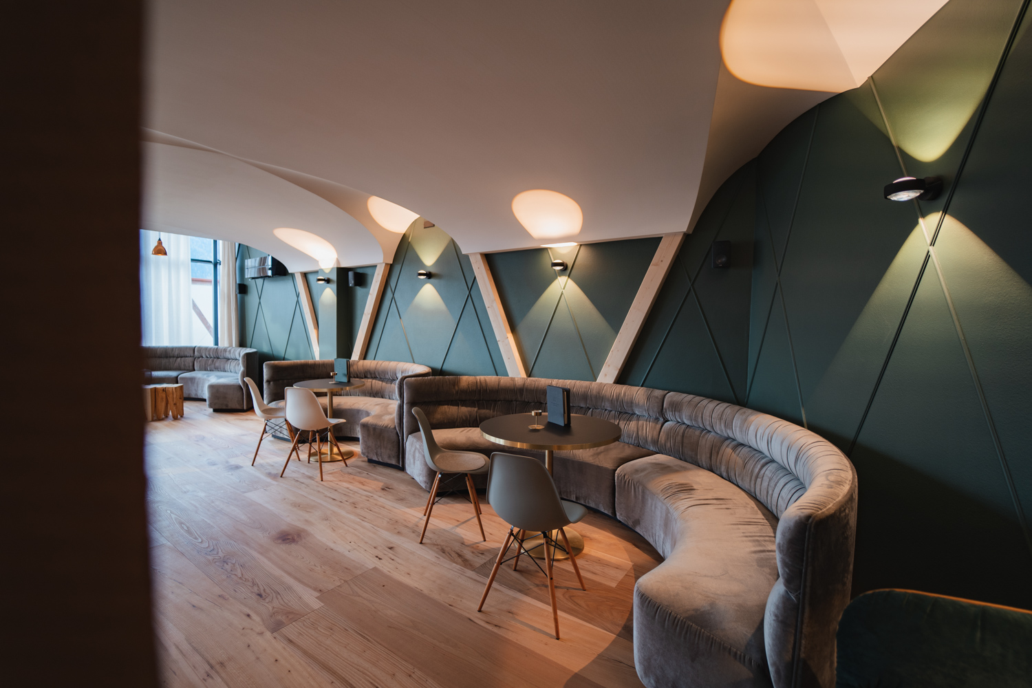 Eleganter Sitzbereich im Garberhof mit geschwungenen Sofas, warmem Licht und modernem Design.