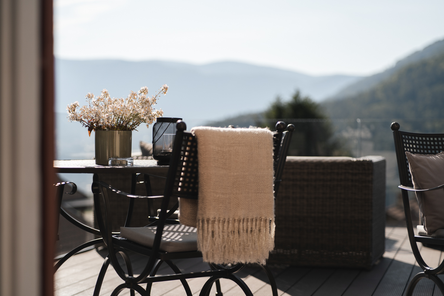 A sunny terrace with comfortable seating, table decorations and views of the South Tyrolean mountain landscape at the Hotel Mair am Ort Living in Partschins near Merano in South Tyrol – an inviting spot to relax outdoors.
