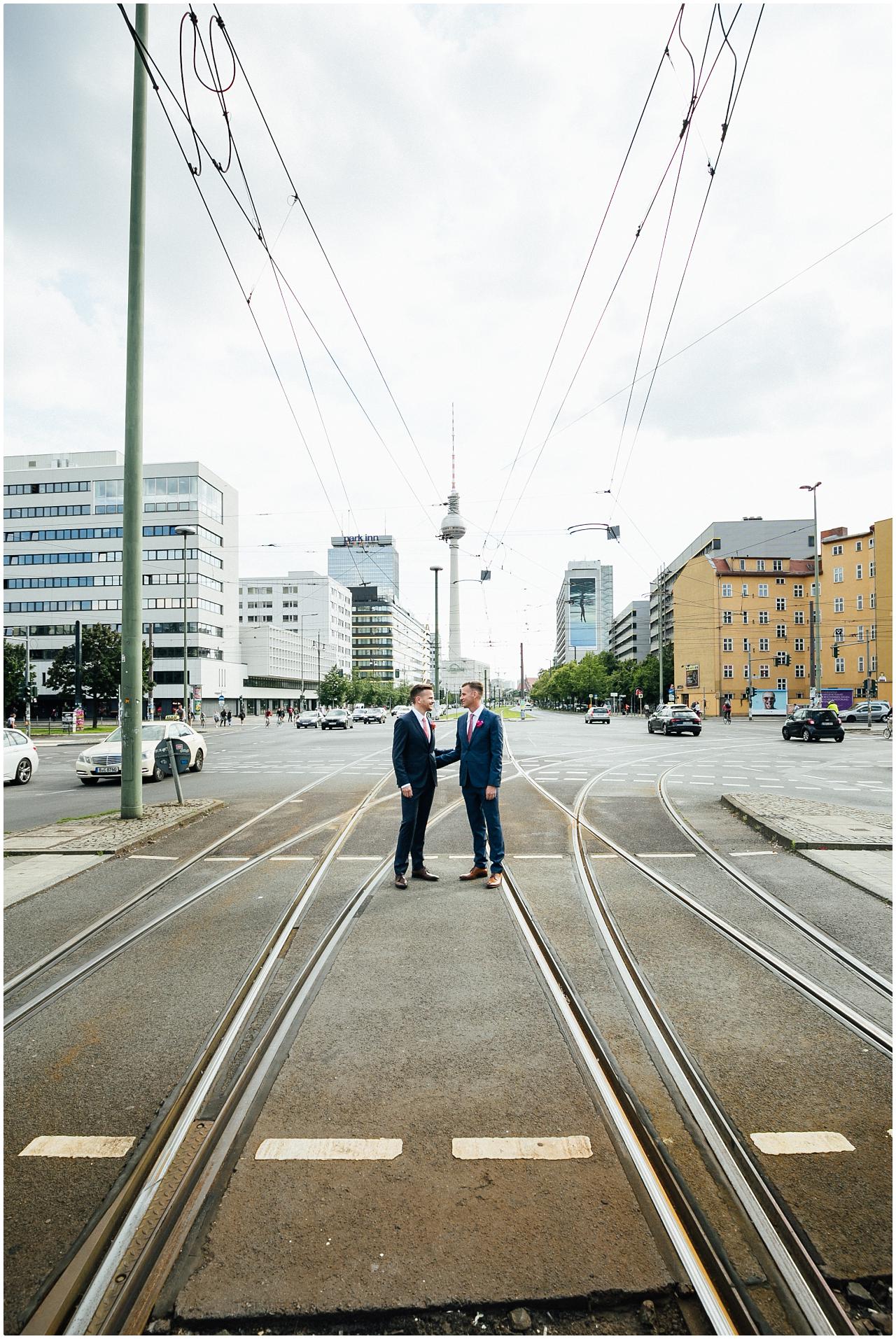 Gleichgeschlechtliches Brautpaar posiert auf den Schienen der Tram vor dem Alexanderplatz in Berlin