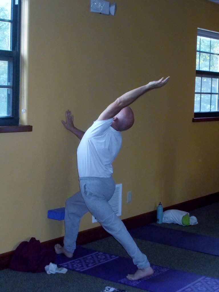 Block placed at the tibia and wall, align the knee and ankle, back leg extended up on the toe, one hand on the wall for support the other reaches up, keep the hips even, legs strong, breath 