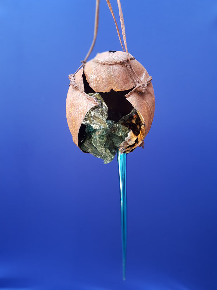 haengendes, explodiertes Stahlei in dem Glas zu sehene ist und aus dem blauer Edelstahl trieft, www.wuensch-art.de