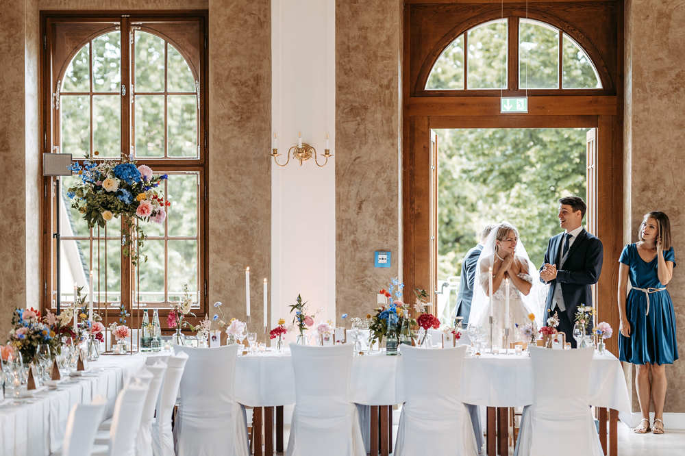 Das frisch vermählte Ehepaar Amely und Fabian betritt unter tosendem Applaus den festlich beleuchteten Saal im Teehaus Altenburg.