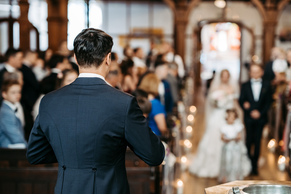 Das Brautpaar Amely und Fabian sitzt Hand in Hand vor dem Altar während der kirchlichen Trauung.