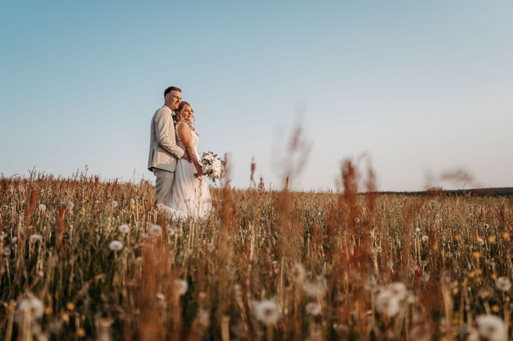Brautpaar tanzt ausgelassen auf einer Naturwiese, eingefangen im authentischen Stil von Lichtecht-Hochzeitsfotografie.
