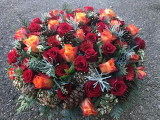 Korb gefüllt mit Frischblumen, Zapfen und winterhartem Grün, 