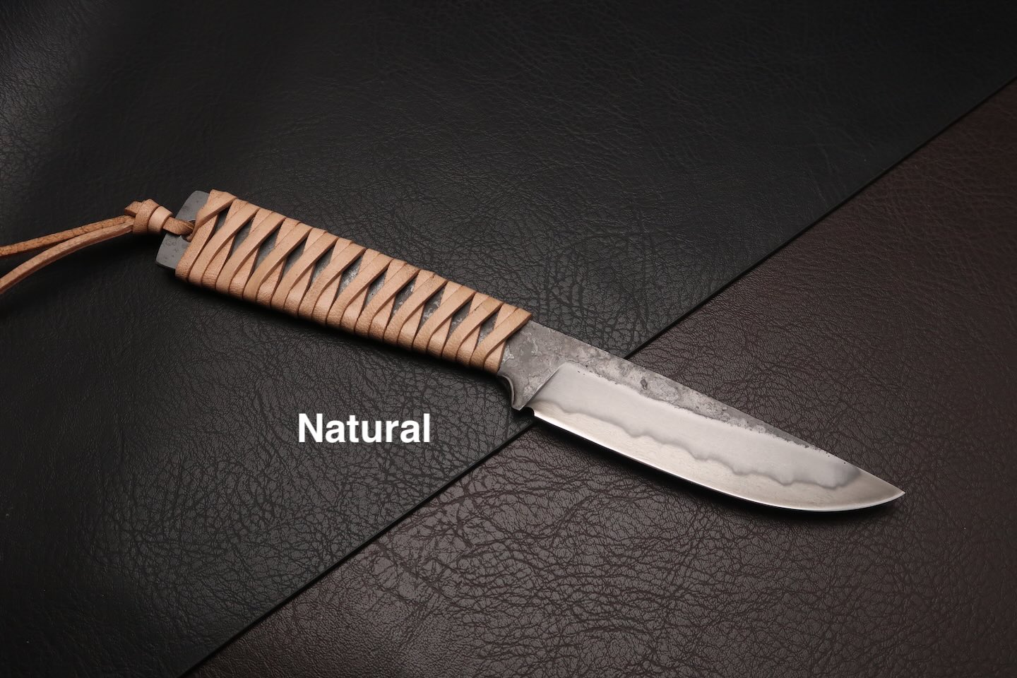couteau avec un manche en cuir tresse et une ligne de trempe