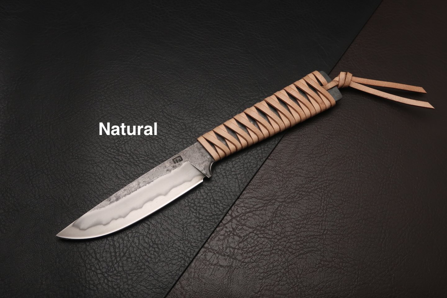 couteau avec un manche en cuir tresse et une ligne de trempe