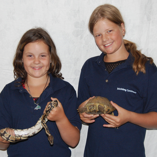 Twee meiden die een meeloopochtend bij stichting carnivora hebben gevolgd en samen op de foto staan met een schildpad en koningspython