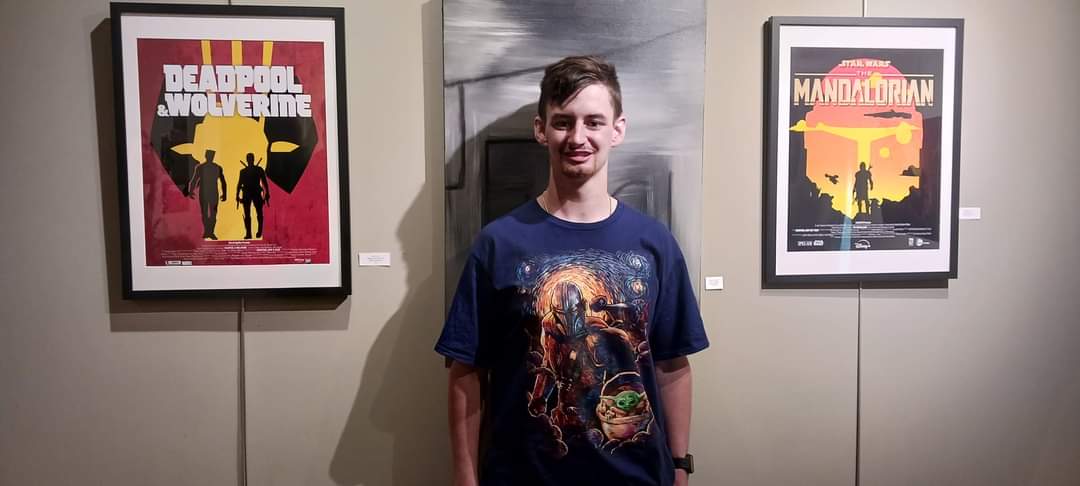 Kaden Doty poses with his graphic design creations