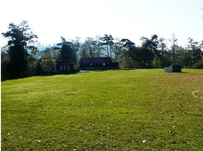 Blick über den Hundeplatz auf das Vereinsheim und das überdachte Außengelände