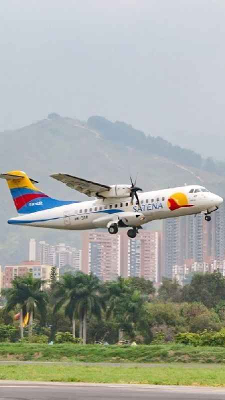 Satena-Flugzeug beim Start am Stadtflughafen Medellin und im Hinterdund die Skyline von Medellin