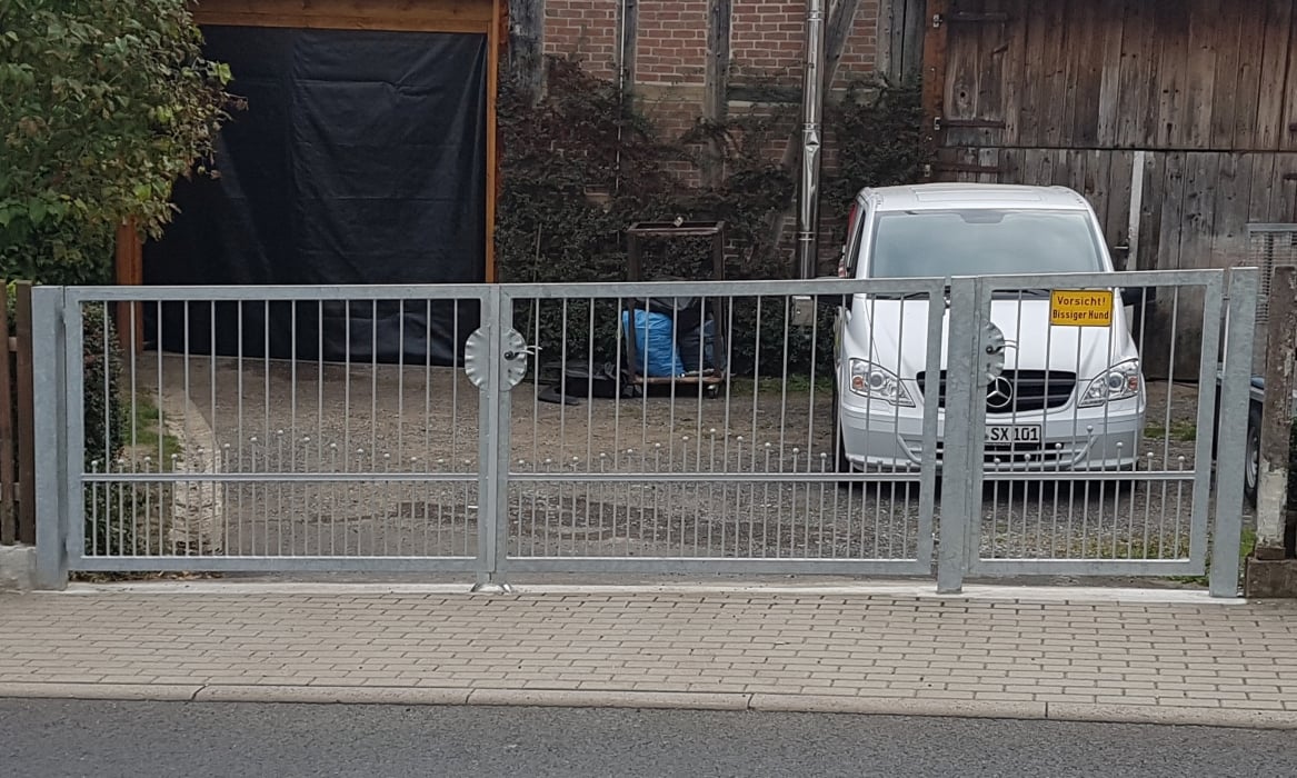 Schmiedeeisernes Drehflügeltor und Tür mit Kugelornamenten angepasst an Gefälle