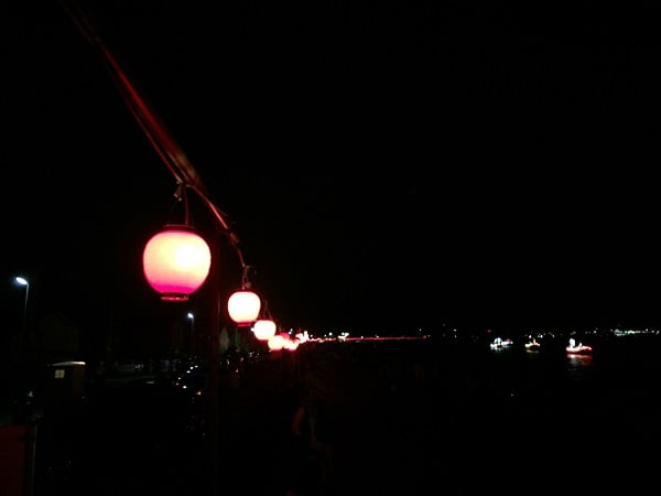 防波堤に沿って提灯が飾られます。海には光る漁船たち。