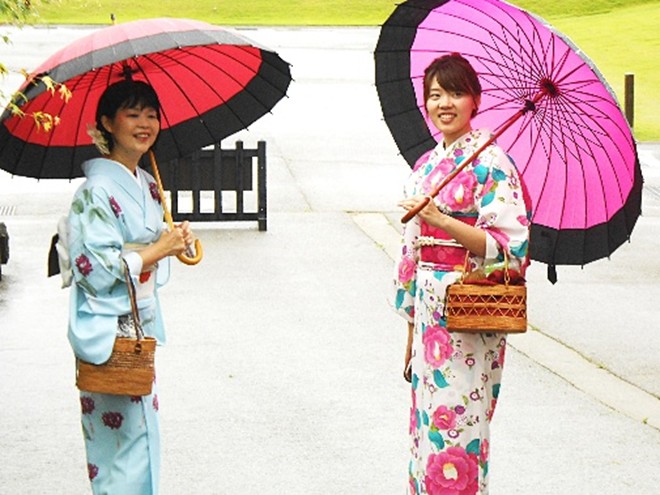 Japanese tourists in a city park dressed in rented kimonos and parazoles on a rainy day, Kanazawa 2017. / 金沢の公園で、レンタルの着物と傘で装う日本人観光客, 2017