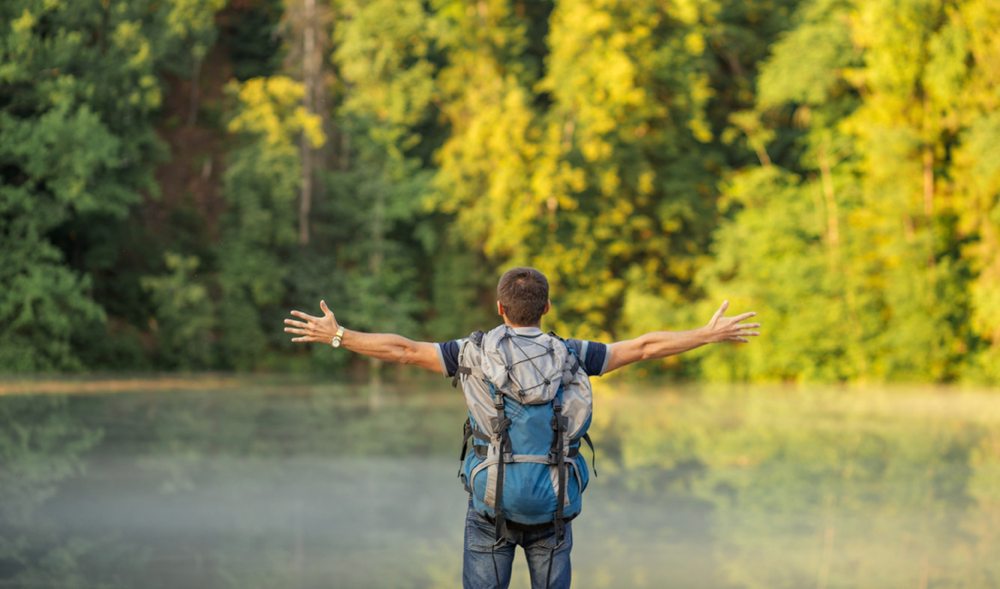 Ein Mensch mit offenen Armen in der Natur, symbolisiert Ermächtigung und Selbstverwirklichung.